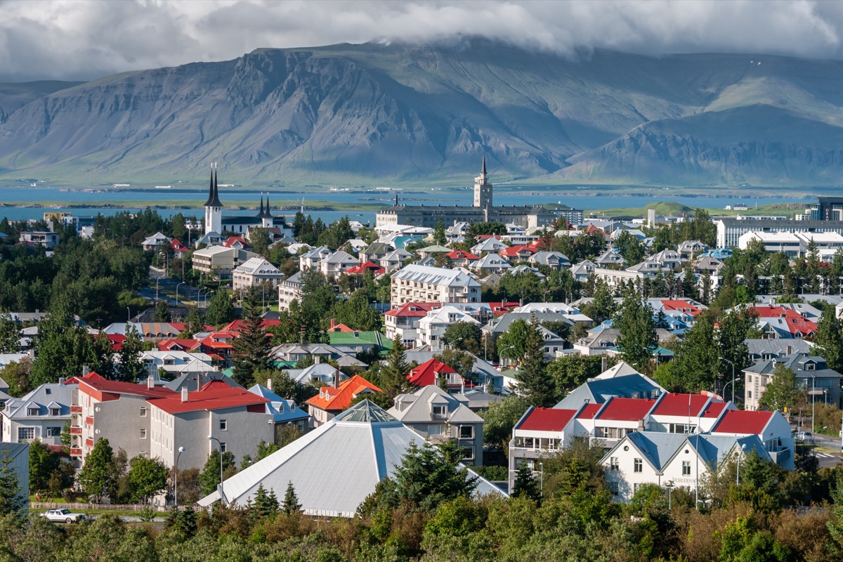 Panorama of Reykjavík with colourful rooftops, a church tower and mountains behind